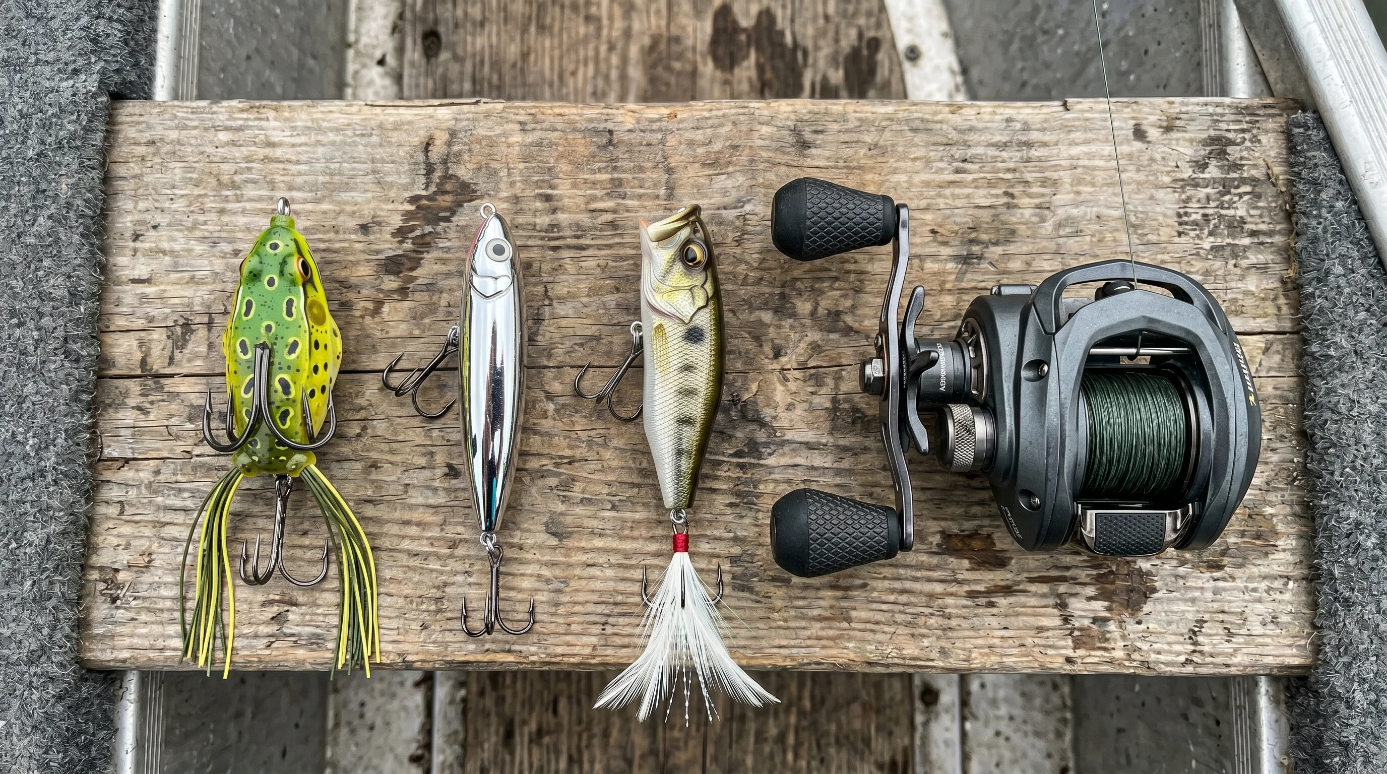 Hollow-body frog, walk-the-dog walker, and surface popper topwater lures arranged on a wooden dock